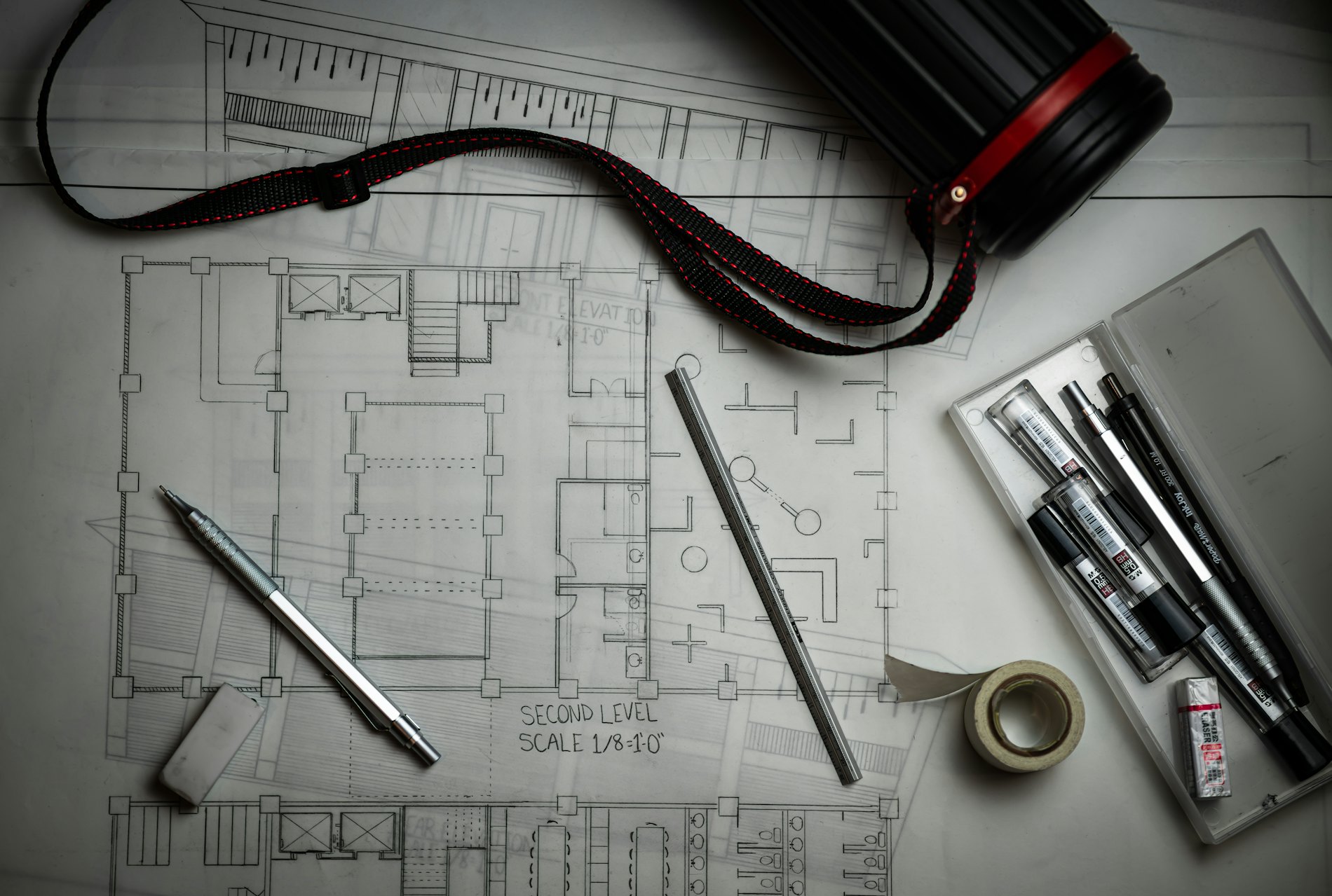 Architectural drawings on a table with drafting tools